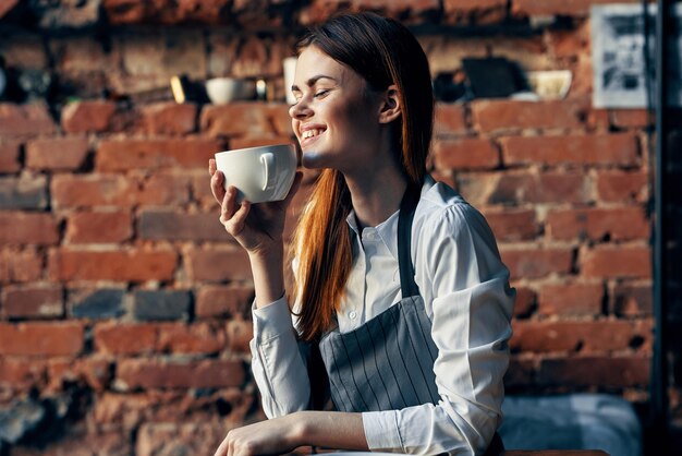 Foto mujer camarero taza de café sentada en la mesa trabajo divertido foto de alta calidad