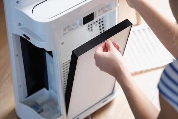 Mujer cambiando el filtro en el sistema de purificación de aire