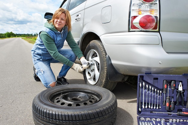 Mujer cambiando una rueda de coche