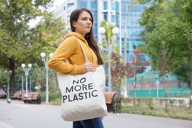 Una mujer camina con una bolsa de tela que dice No más plástico