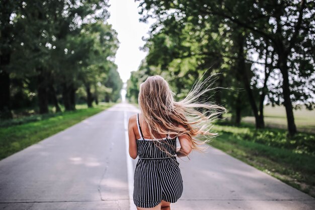 mujer camina por la carretera entre el bosque nueva vida en el verano El concepto de un brillante