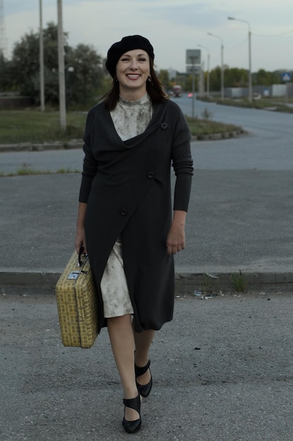 una mujer camina por la carretera con una maleta, un viaje, esperando un viaje