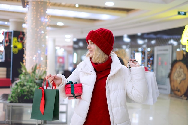 Mujer camina por el centro comercial con compras como regalo para la Navidad