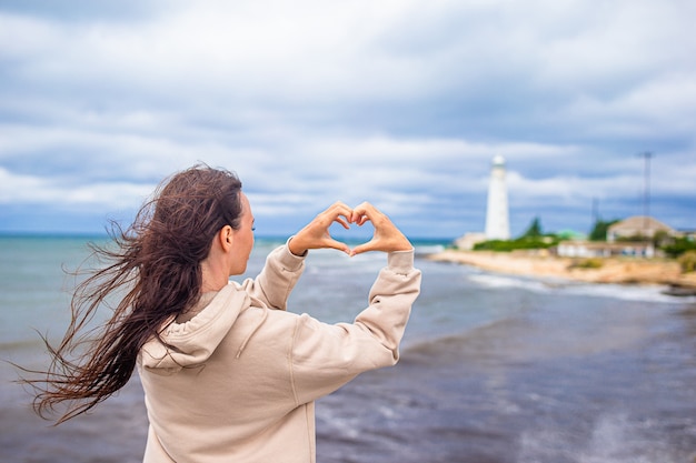 Mujer camina hacia el faro y hace corazón