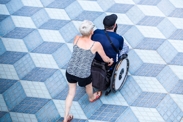 Foto mujer camina con un hombre discapacitado en silla de ruedas, paseo relajado al atardecer