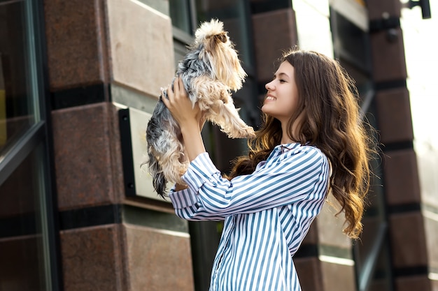 Mujer camina con un perro en la calle de la ciudad.