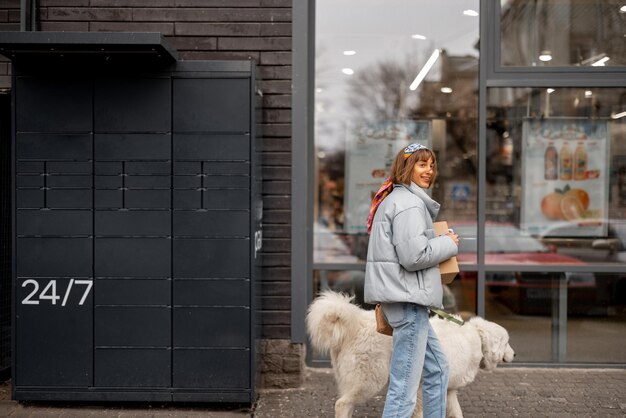 Mujer camina con un perro y un paquete en una calle