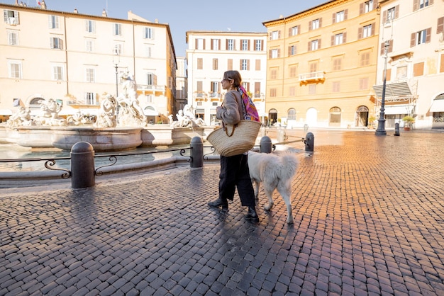 Mujer camina con perro pastor italiano en la plaza navona en roma