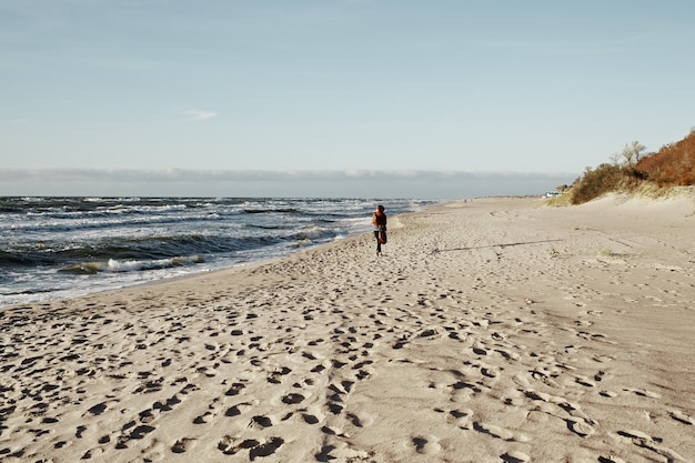 Mujer camina en la playa al atardecer.