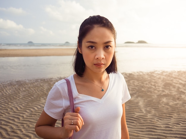 La mujer camina en la playa al atardecer