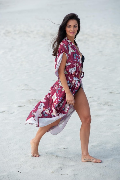 Una mujer camina por la playa con un vestido floral.