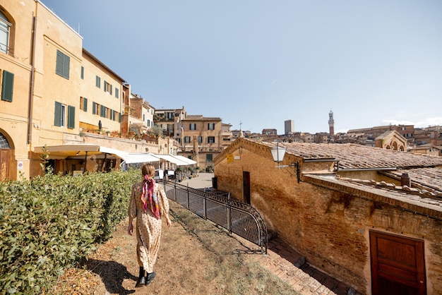 Mujer camina sobre el fondo del paisaje urbano del casco antiguo de siena en italia