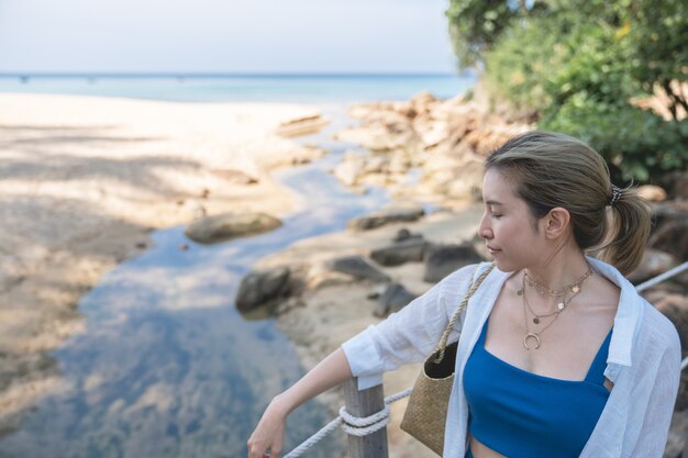 Foto mujer camina sobre el puente del muelle de madera junto a la playa en el mar.