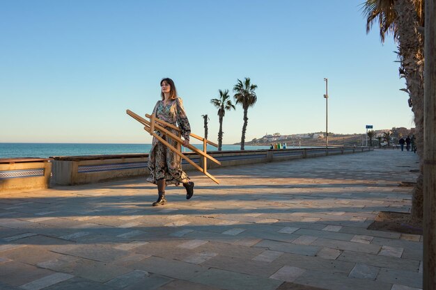 Foto mujer caminando por la acera con un caballete