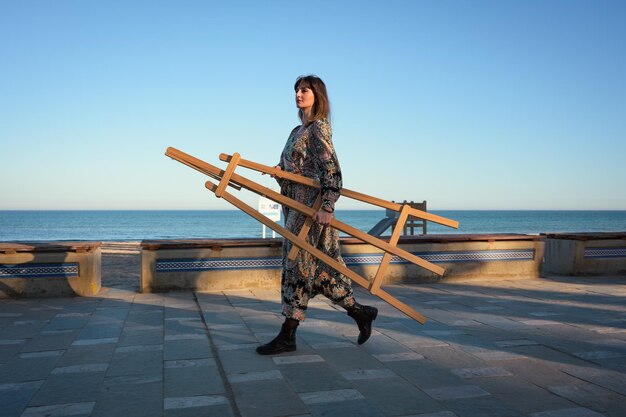 Mujer caminando por la acera con un caballete