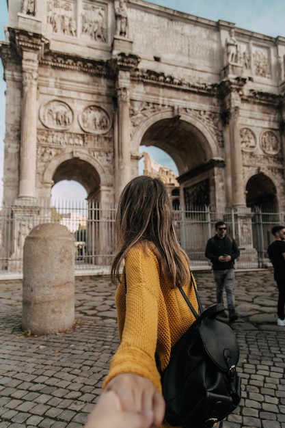 mujer caminando hacia el arco de Adriano con jersey amarillo