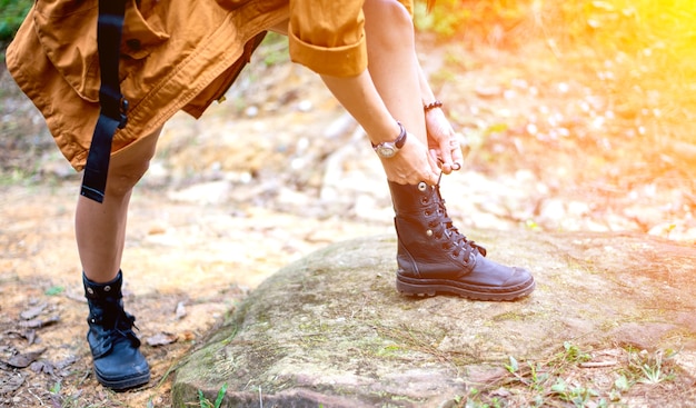 Mujer caminando atar cordones de los zapatos en la pista forestal