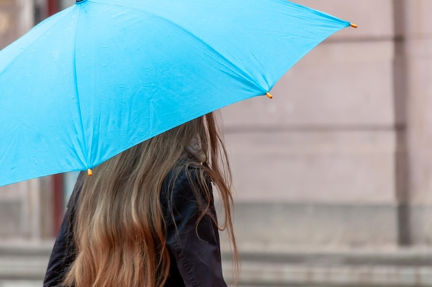 Mujer caminando por la calle bajo la lluvia con un paraguas en la mano Personas reales