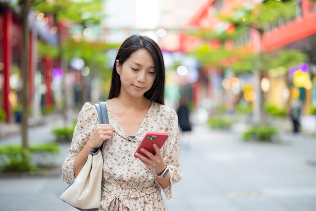 Mujer caminando por la calle con su teléfono