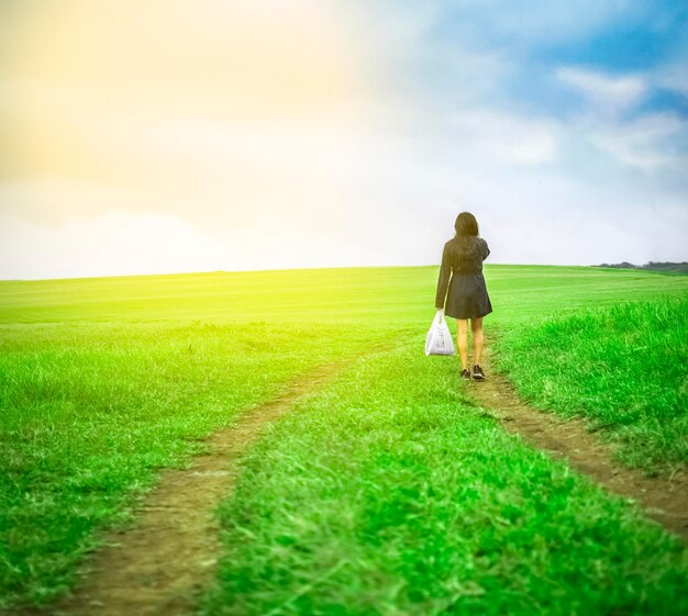 Mujer caminando en el campo con bolsas de compras mujer caminando en un camino en el campo