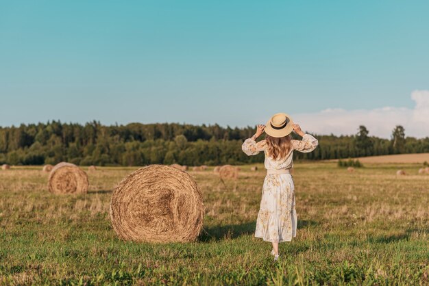 Mujer caminando en campo con pajares