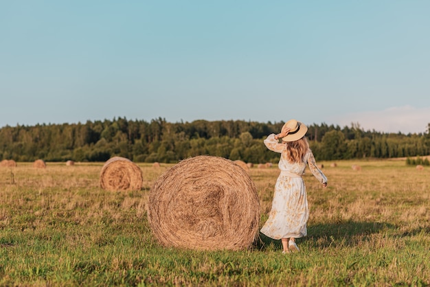 Mujer caminando en campo con pajares