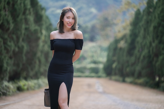 Mujer caminando por la carretera a través del bosque de pinos.