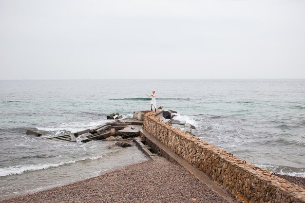 Mujer caminando cerca del mar Modelo femenino con cabello corto caminando en un día nublado Concepto de tiempo libre de la naturaleza