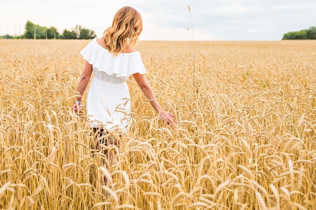 Mujer caminando en el concepto de trigo sobre la naturaleza, la agricultura y las personas