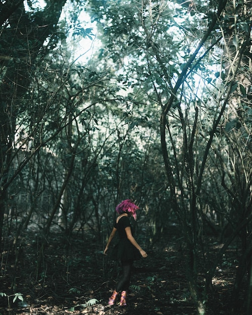 Foto mujer caminando contra los árboles en el bosque