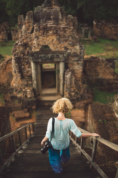 Foto mujer caminando por las escaleras contra el viejo templo