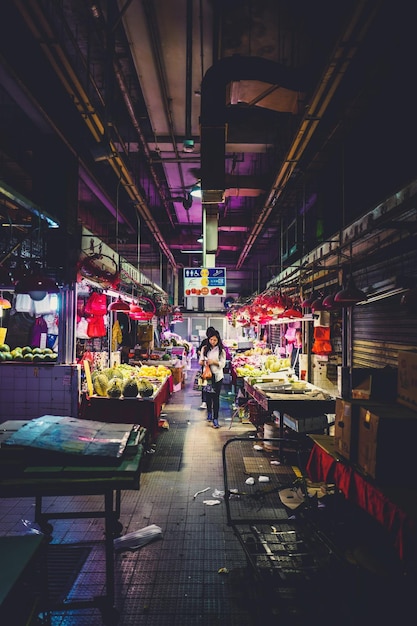 Mujer caminando en medio de un puesto de mercado iluminado