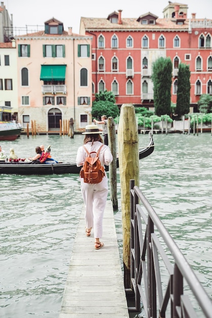 Mujer caminando por el muelle de madera mirando el gran canal de venecia