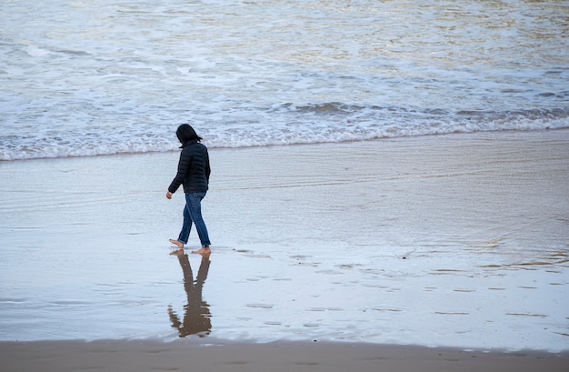 mujer caminando por la orilla del mar