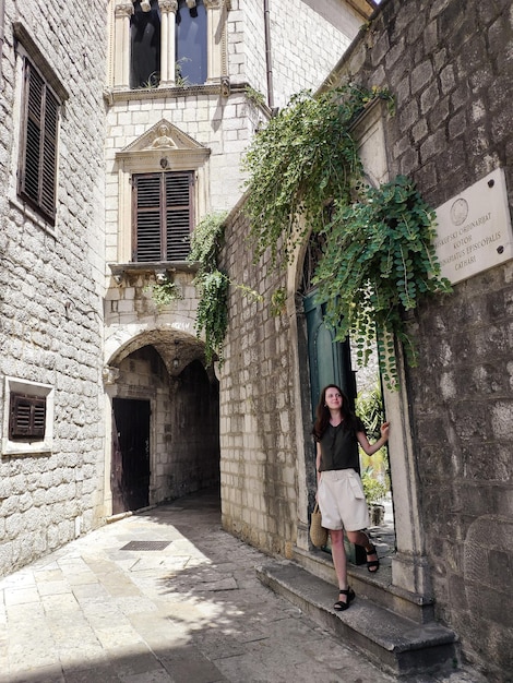 Mujer caminando en una pequeña calle con edificios de piedra en el casco antiguo de Kotor, Montenegro