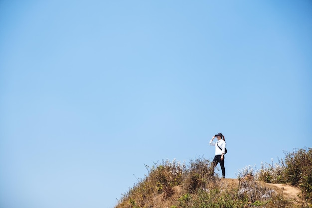Una mujer caminando y de pie en la cima de las montañas con fondo de cielo azul