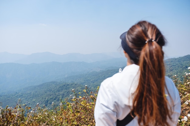 Una mujer caminando y de pie en la cima de las montañas mirando una hermosa vista