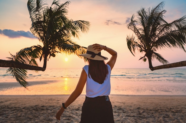 Mujer caminando en la playa al atardecer