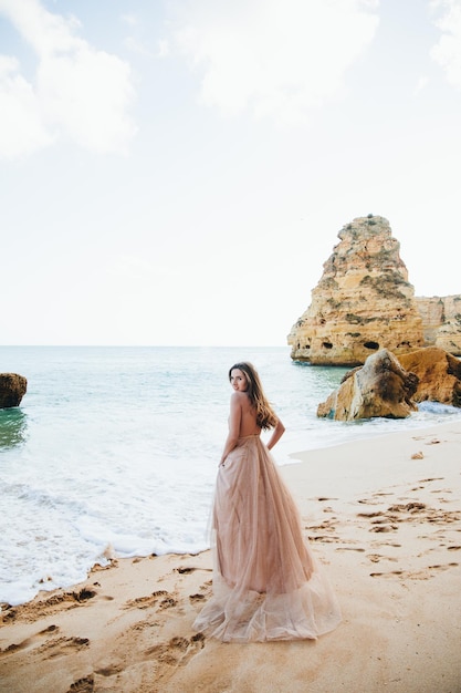 Mujer caminando por la playa contra las rocas y el océano