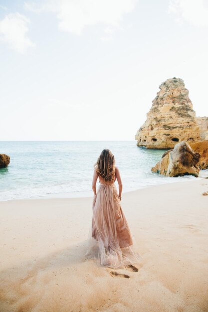 Mujer caminando por la playa contra las rocas y el océano