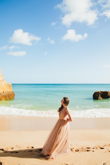 Mujer caminando por la playa contra las rocas y el océano