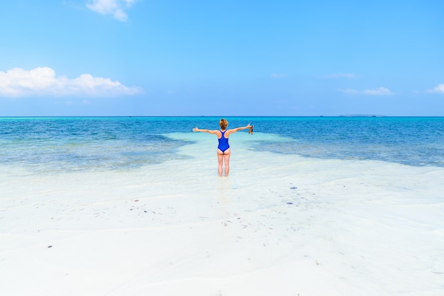 Mujer caminando en la playa tropical. Vista trasera arena blanca