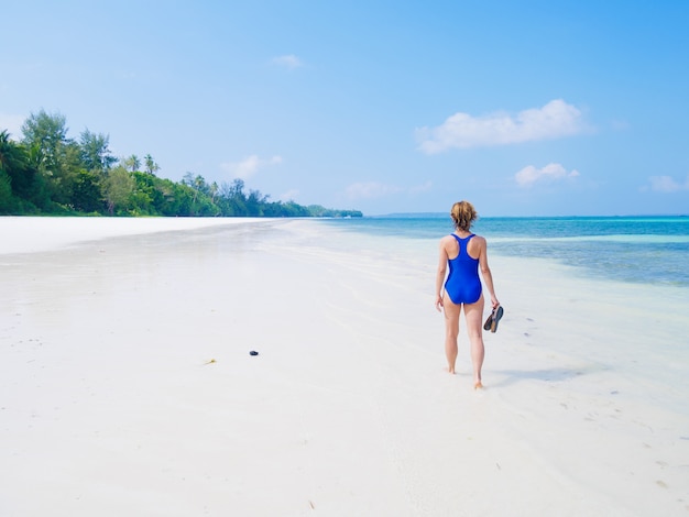 Mujer caminando en la playa tropical. Vista trasera playa de arena blanca turquesa agua transparente mar caribe personas reales. Indonesia Kei Islands Moluccas destino de viaje.