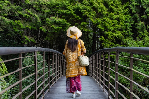 Foto mujer caminando por el puente de madera en el bosque