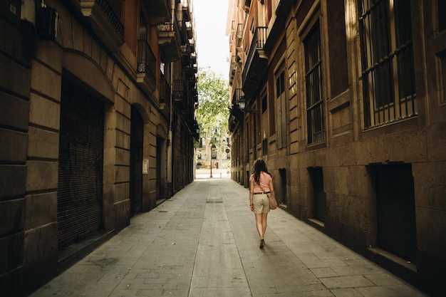 Mujer caminando por un sendero entre edificios en la ciudad