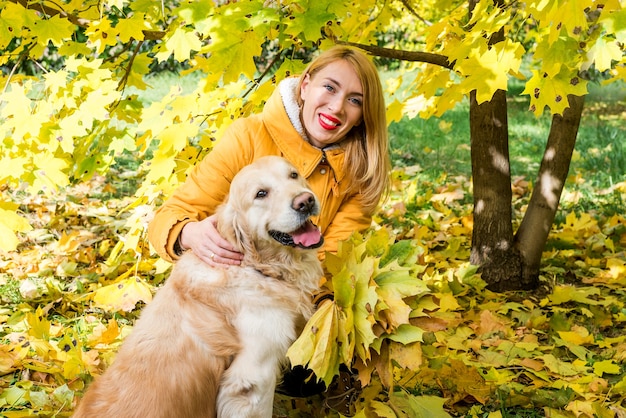 Mujer caminando con su perro perdiguero entre otoño hojas amarillas