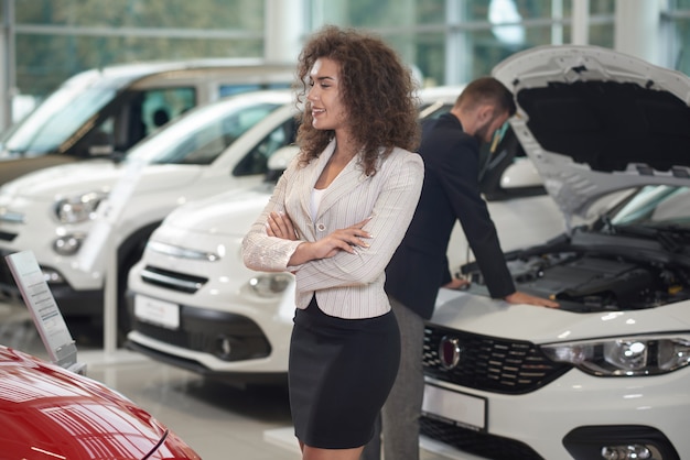 Mujer caminando en la tienda de automóviles, gerente de trabajo.