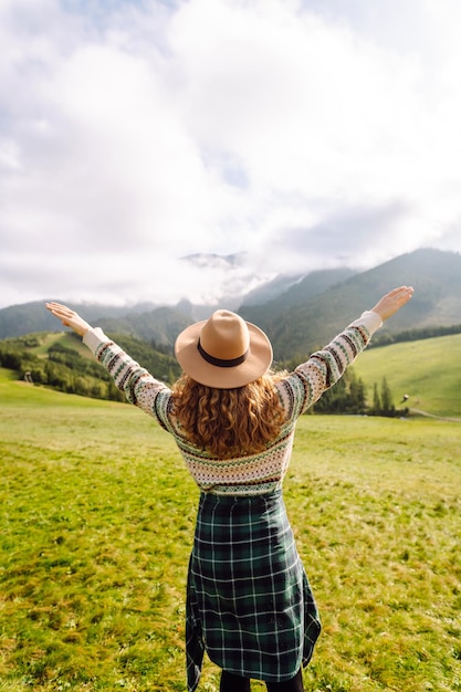 Mujer caminando a través del valle de hierba verde en el fondo grandes montañas concepto de descanso