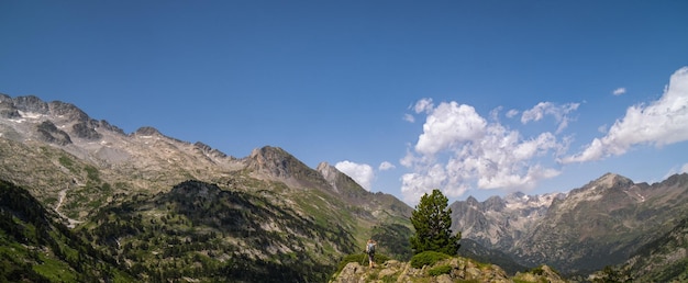 Mujer caminante en la cima de una montaña viendo el paisaje montañoso de los Pirineos