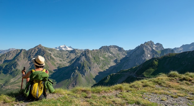 Mujer caminante descansando un momento y mirando una montaña